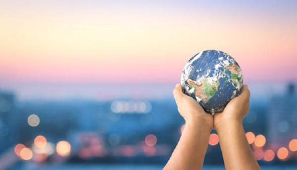 A pair of hands hold up a replica of the Earth